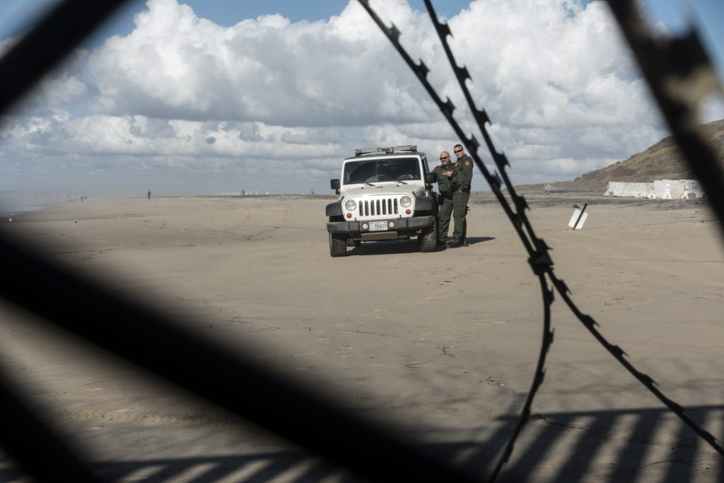 U.S. Border Patrol agents can be seen through a border wall and wire between the U.S. and Mexico.