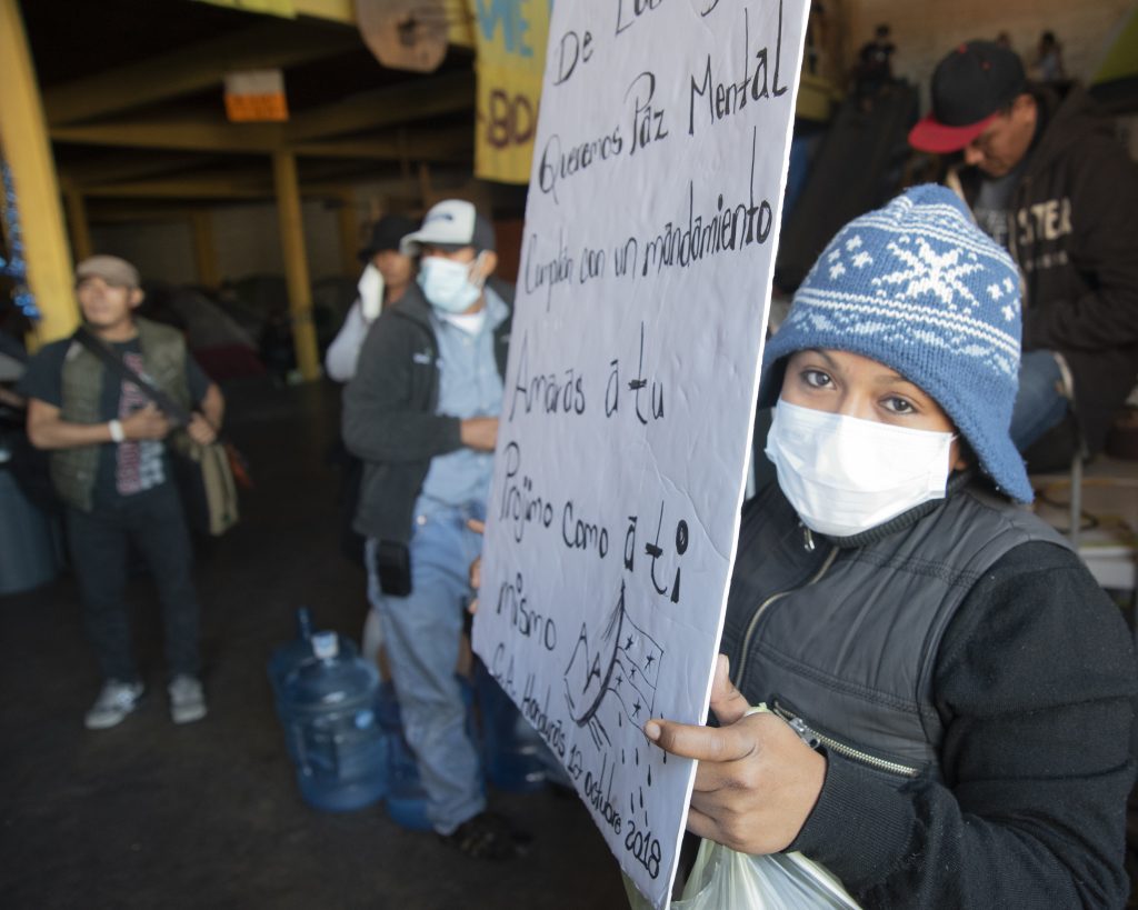A Honduran immigrant displays a sign inside an immigrant shelter in Tijuana. She left Honduras to get away from a gang that killed the father of her child.