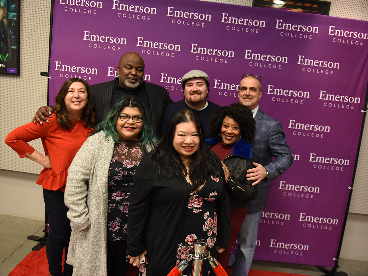 seven people in front of Emerson College step and repeat