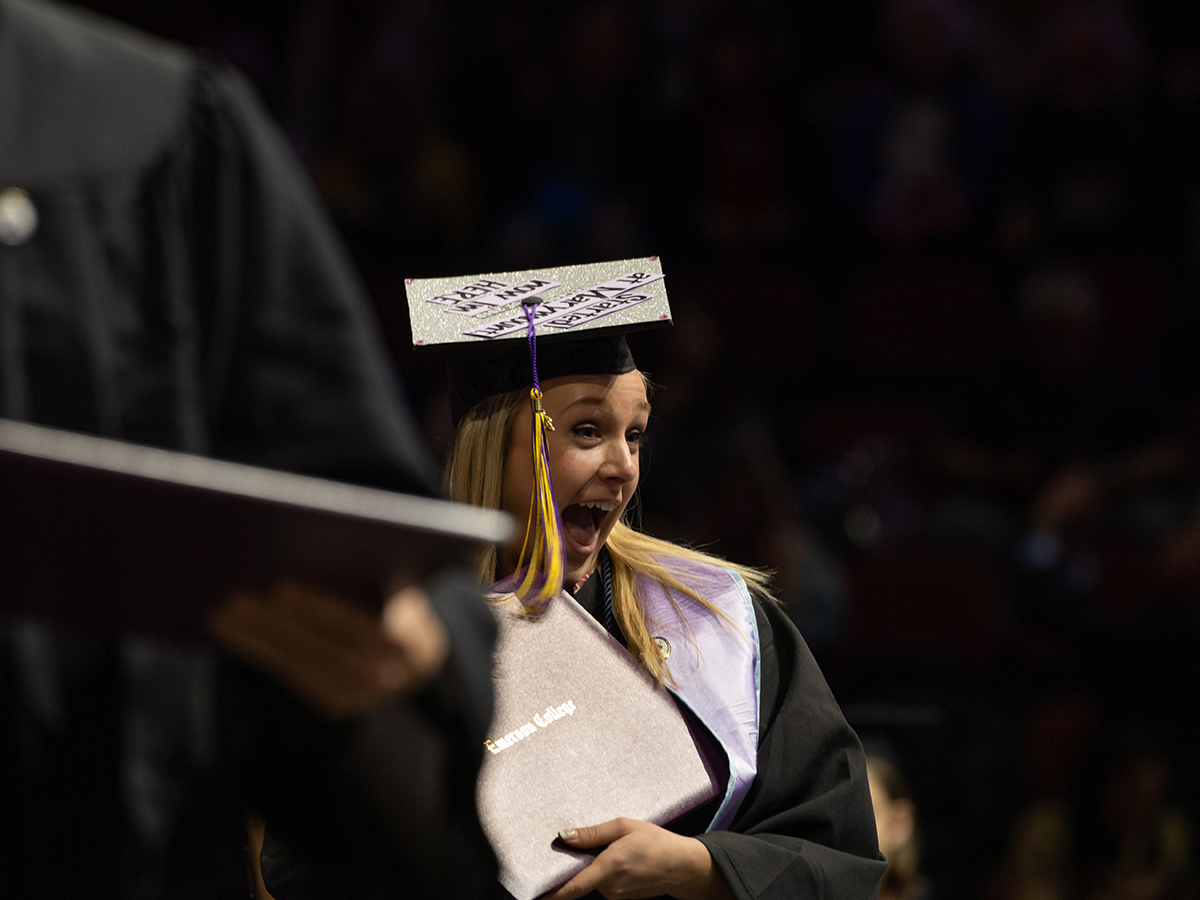 Woman in cap and gown shows off diploma