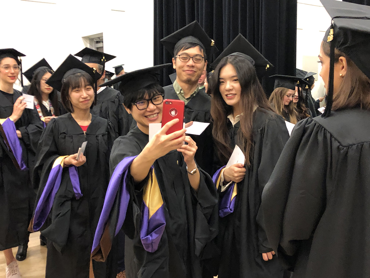 Students took selfies while waiting to go into the Paramount Theater for the School of the Arts Hooding Ceremony.