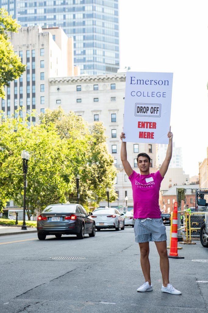 A student holds a sign directing drivers