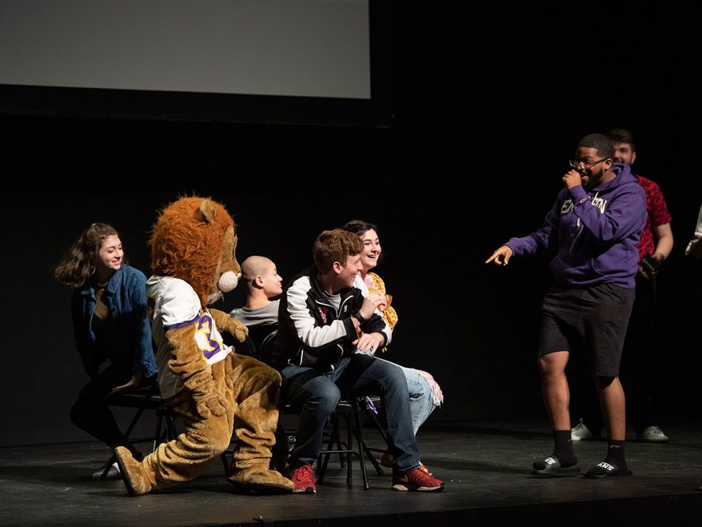 Students and the Emerson College mascot Griff sit on chairs