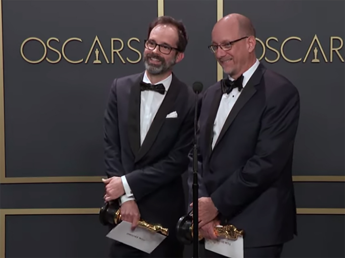Andrew Buckland and Michael McCusker talk at a microphone after winning Oscars