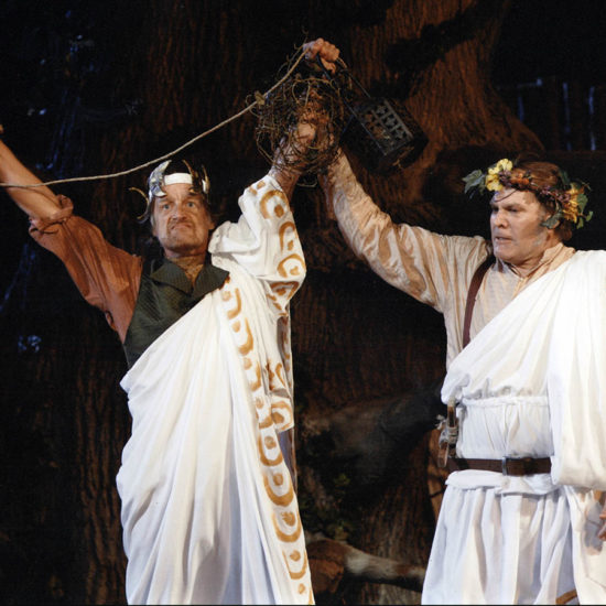 Two men wearing yogas hold their hands together in the air.