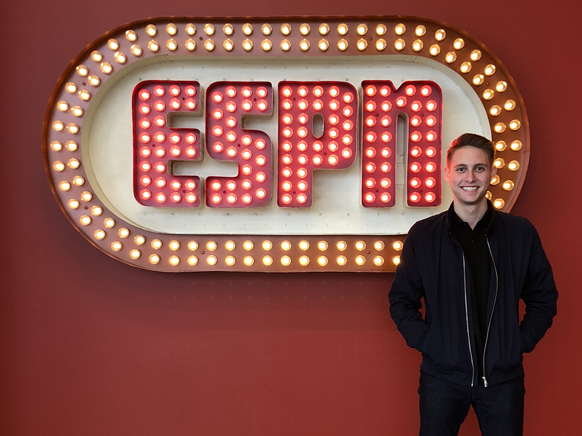 Zach Rothfeld stands in front of neon sign that says ESPN