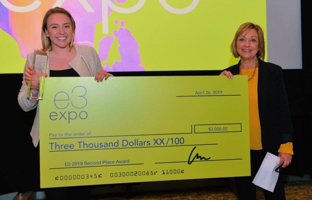 Two women stand with a giant oversized check