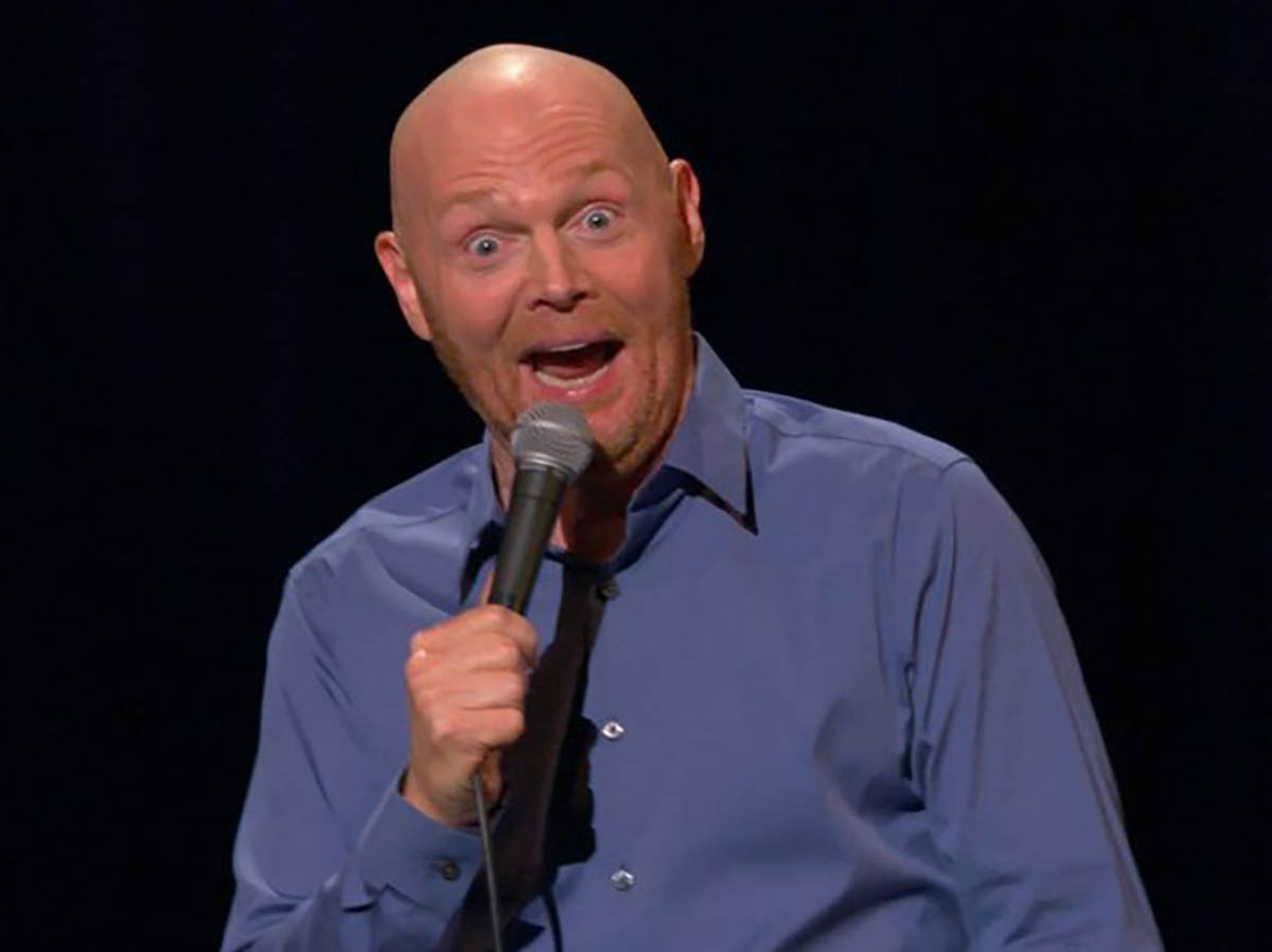 A man holds a microphone while performing standup comedy