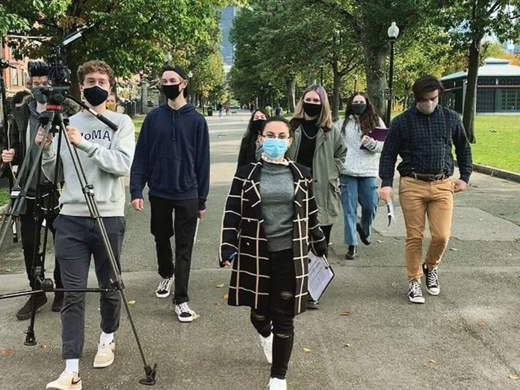 students in masks with film gear walking down street