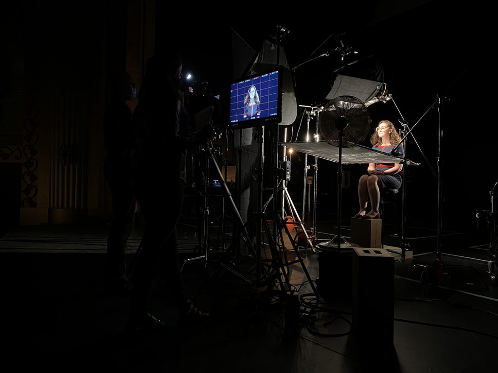 Student sits in sound stage surrounded by film equipment