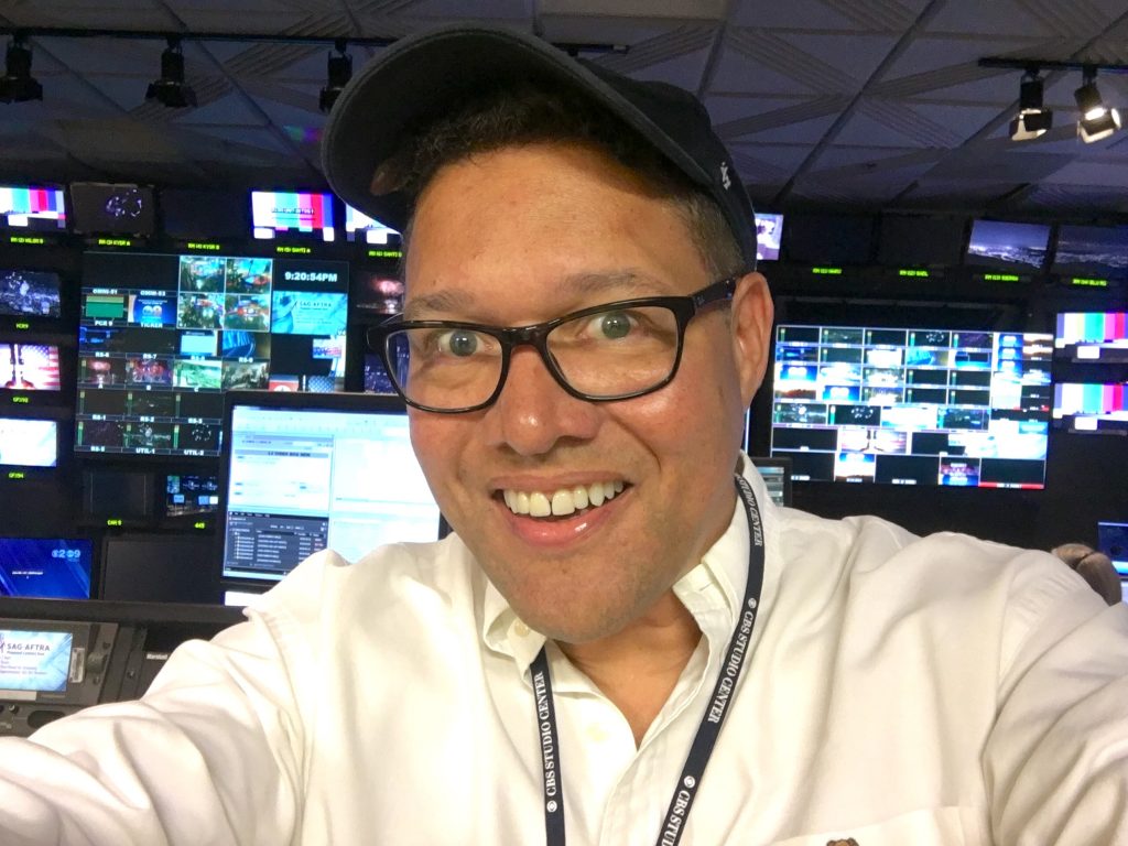 Charles Stewart in baseball cap in news studio