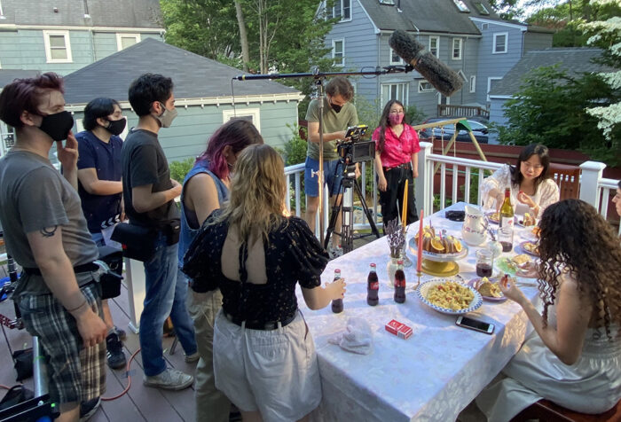 cast and crew around a table covered with food on a deck