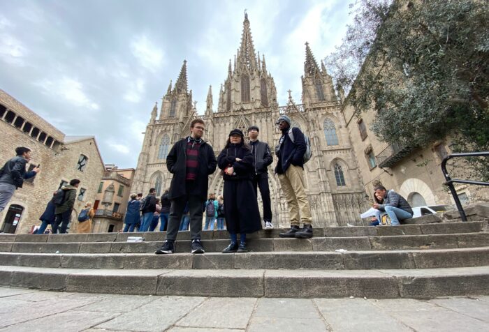 Students stand on steps in front of a church