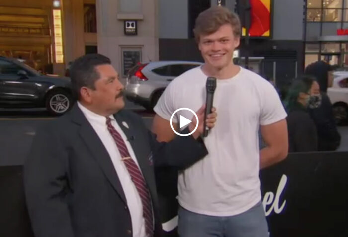 man on LA street holding microphone to young man's mouth