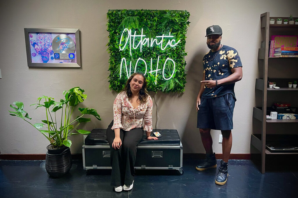 Brianne Guanaga sitting on bench, Justin Allen standing beside her in Atlantic Records office