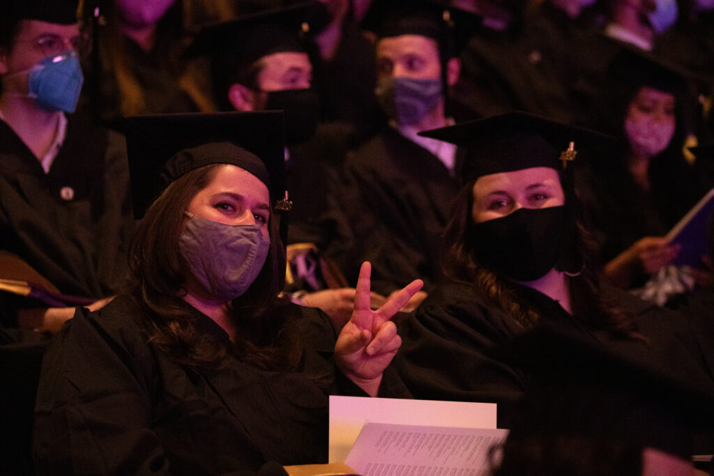A graduate shows a peace sign