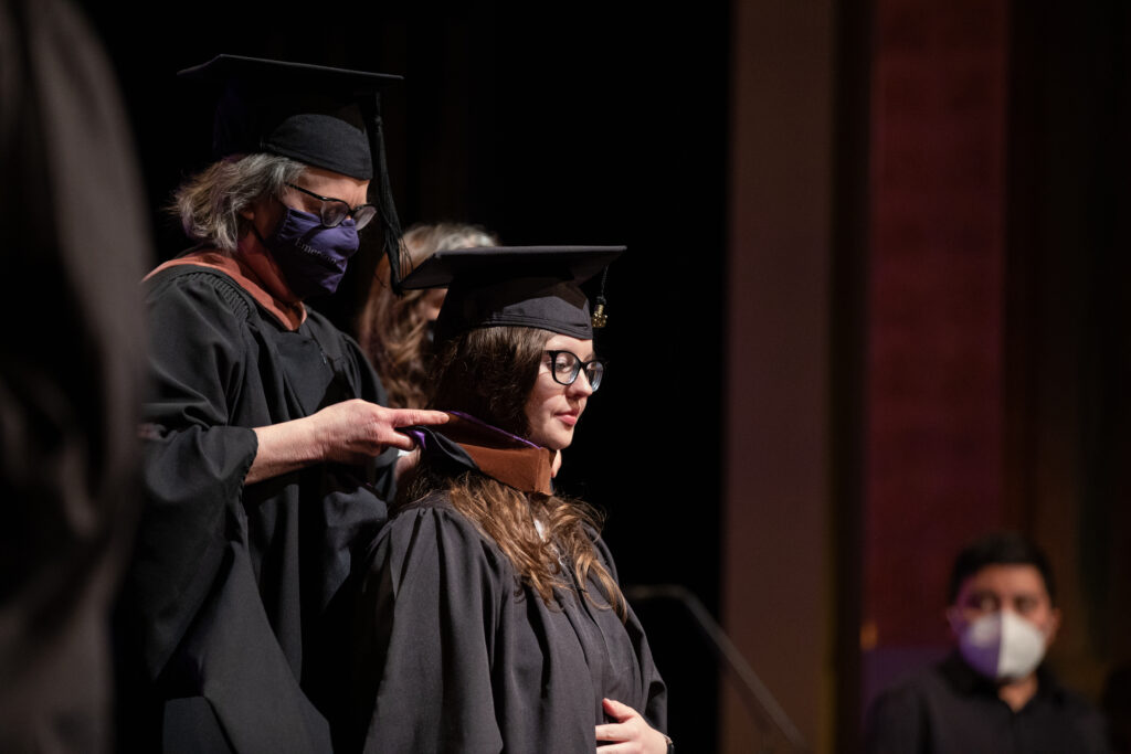 A graduate receives their graduation hood