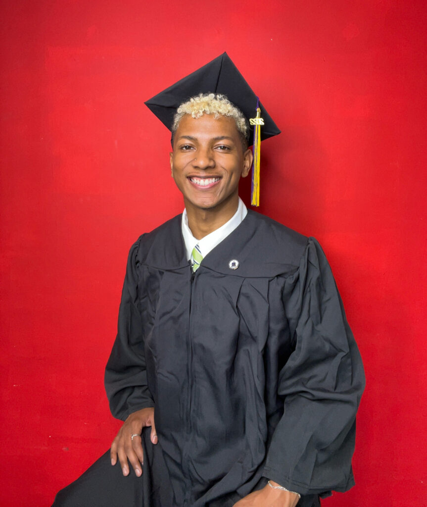 man in cap and gown in front of red background