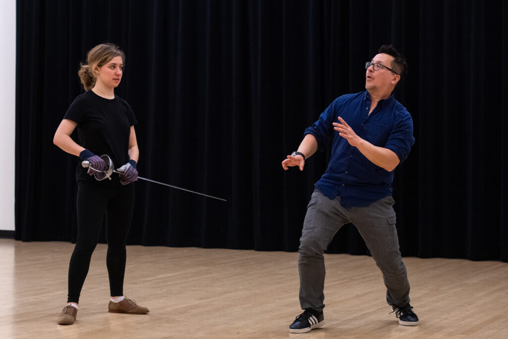 Ted Hewlett pretends to duck while teaching a student stage combat