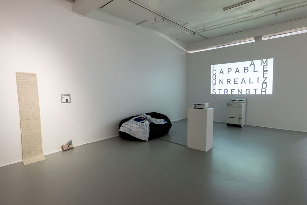 black bed against wall of white room, featuring stove and projected words
