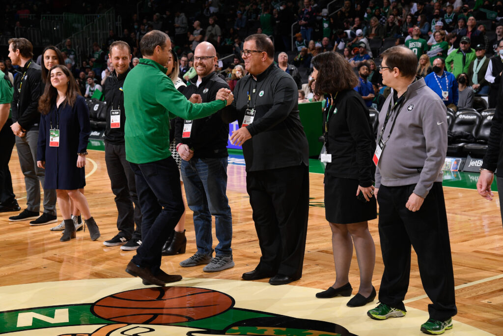 Eddie Palladino shakes a person's hand in a line of Celtics employees at center court