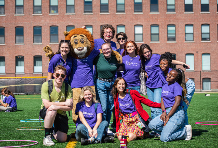 students in purple Ts pose with Griff the Lion on Rotch Field