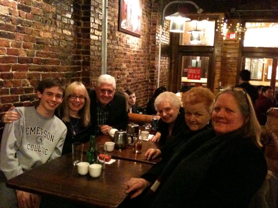 Alex Ates, his parents and godparents and Maureen Shea sit at tables in a restaurant