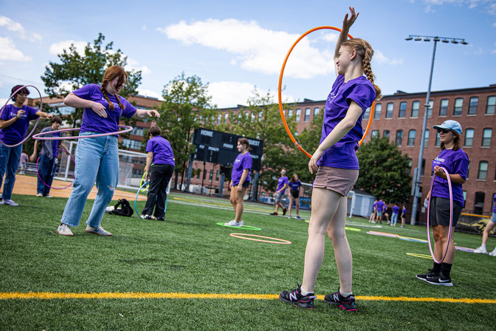 women in purple Ts play with hula hoops