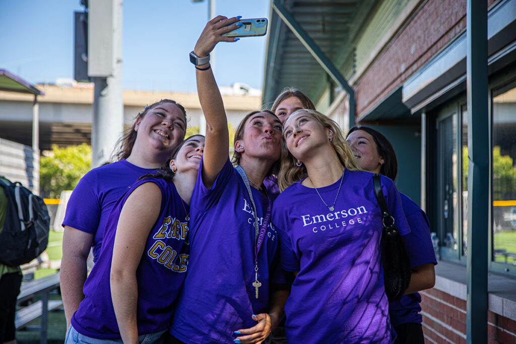 young women in purple Ts look up at phone for selfie