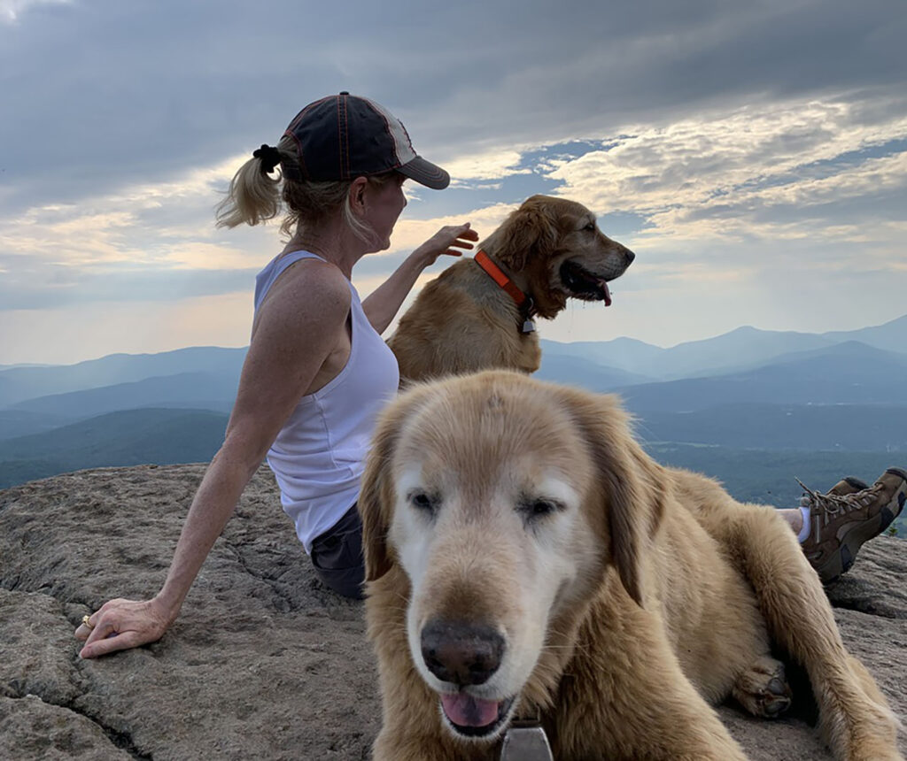 Aynsley Floyd with two golden retrievers atop a mountain