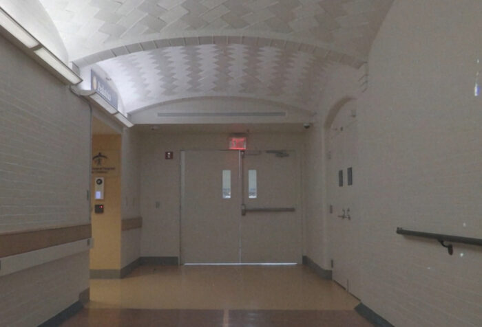 still frame of double doors at the end of a long hospital corridor