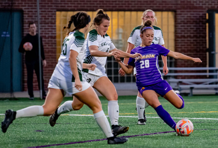 An Emerson women's soccer player shoots against two opponents