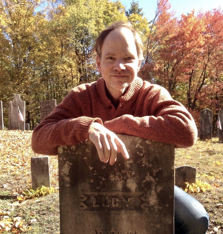 William Orem kneels by a tombstone that says Lucy