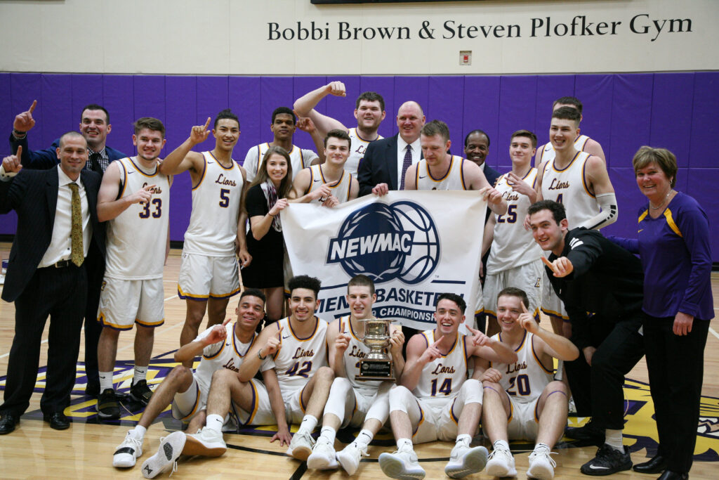 Men's basketball team and staff pose after winning the NEWMAC championship