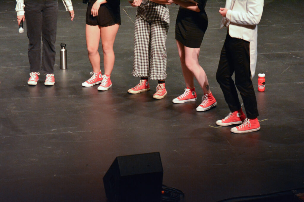 The feet of performers showing red Chuck Taylor shoes