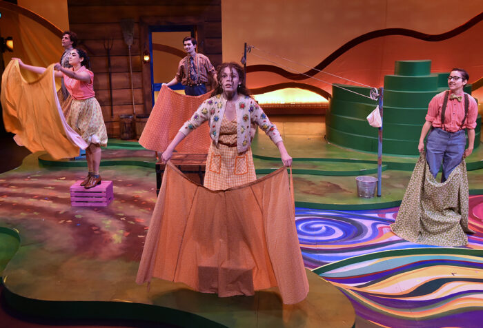 Four actors hold cloths on stage featuring colorful setin Old Jake's Skirts