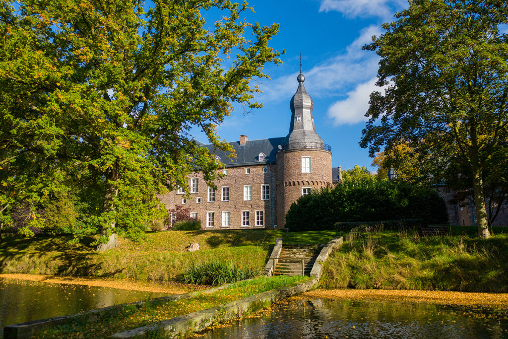 kasteel well with moat in foreground, framed by trees