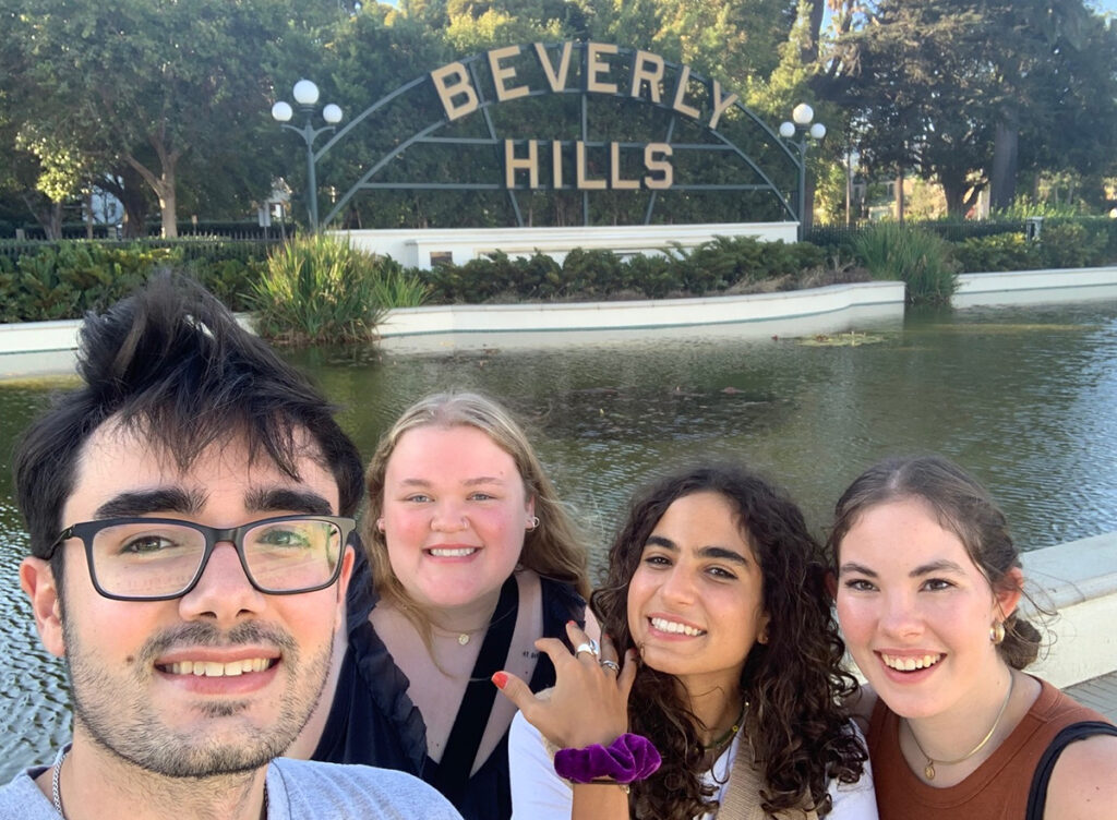 Four students in front of water feature with metalwork "Beverly Hills" sign behind them