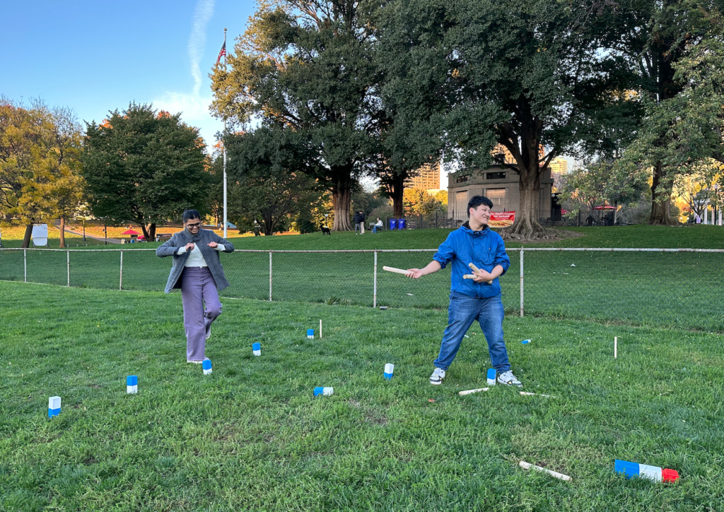 Urja Patel and Freddy Wang play the lawn game kubb on the Boston Common