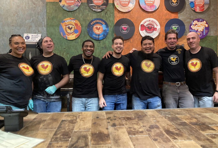 seven people in black t-shirts with Roundhead Brewing logo stand behind wood bar