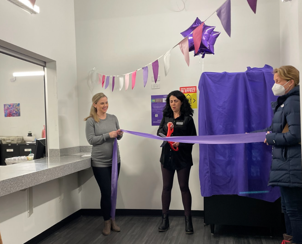 Laura Owen and Marin Smith hold onto the ribbon while Lisa Viveiros cuts it during the emergency contraception vending machine grand opening
