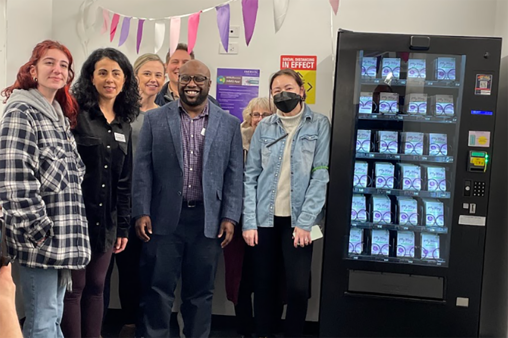 Brandin Dear with staff and students next to the emergency contraception vending machine