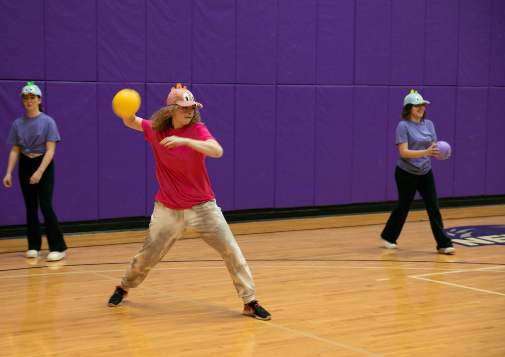 Three team members with hats play dodgeball