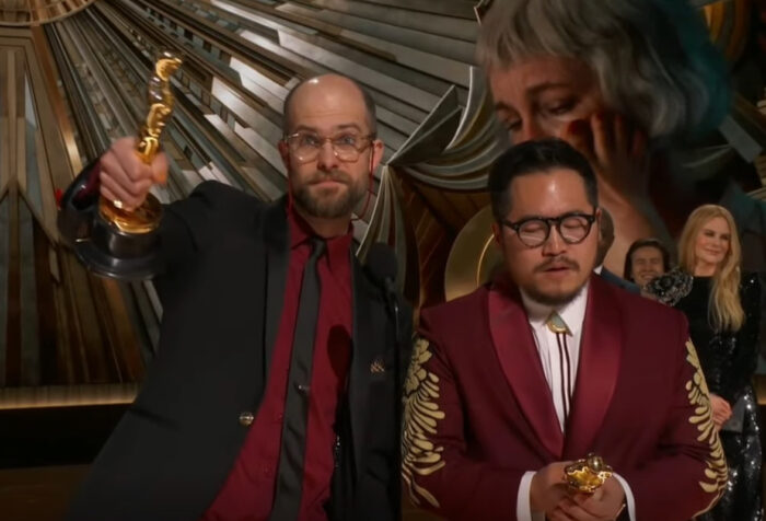 Scheinert holds out Oscar while Kwan speaks into mic on Oscars stage