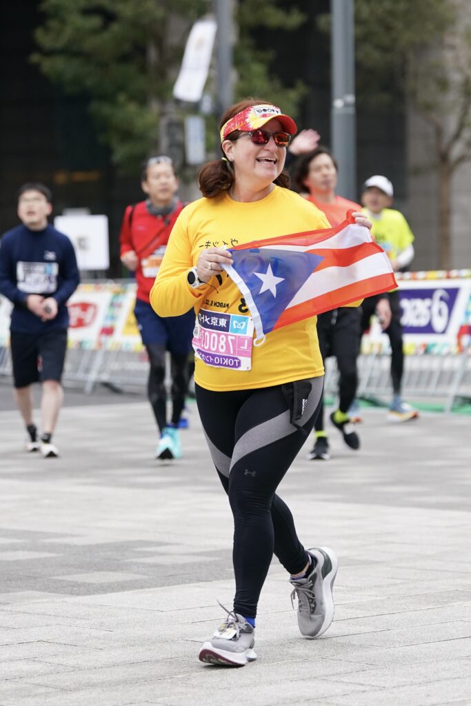 Nydia Bou holds the Puerto Rico flag while running 