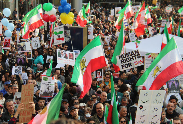 protestors holding signs and Iranian flags