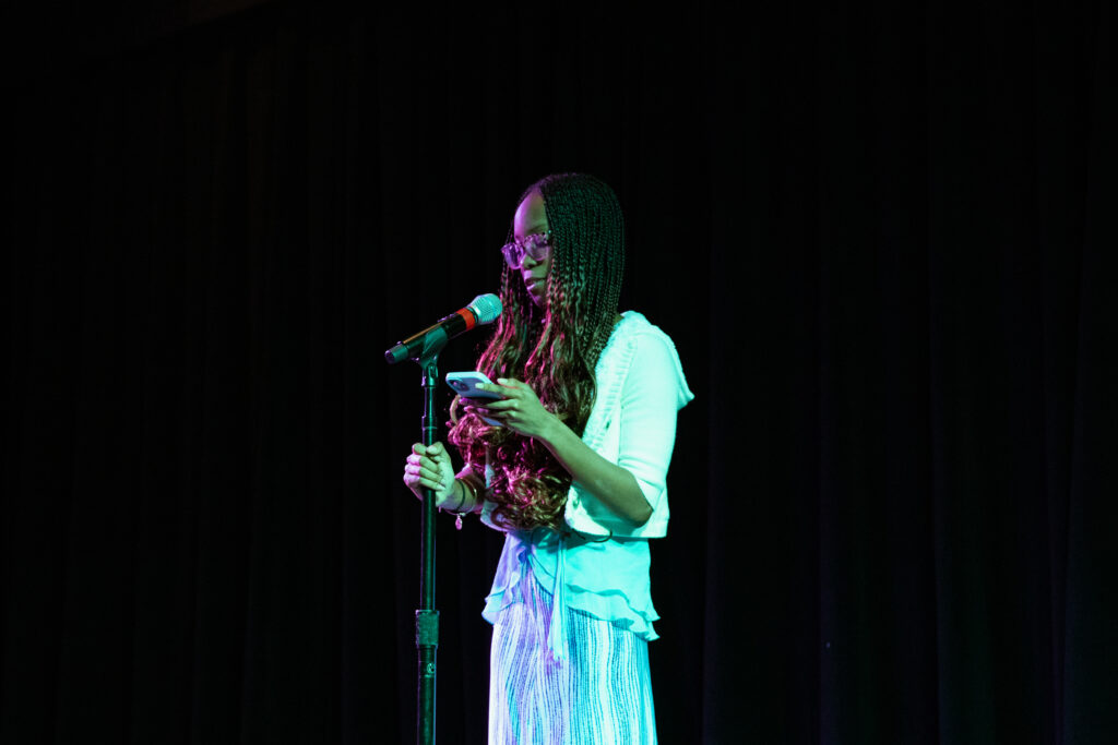 A person performs poetry with a microphone on stage