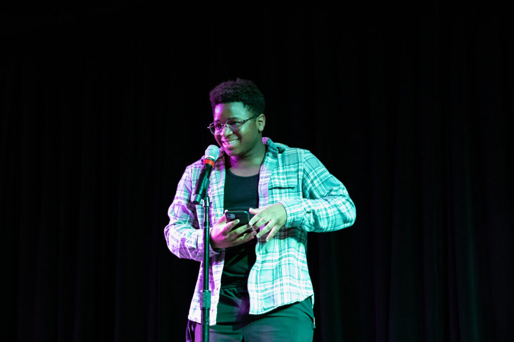 A person smiles as they perform poetry