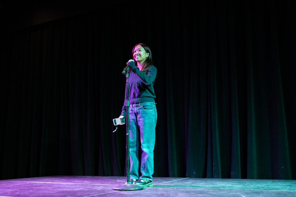 A person speaks on stage while holding a microphone