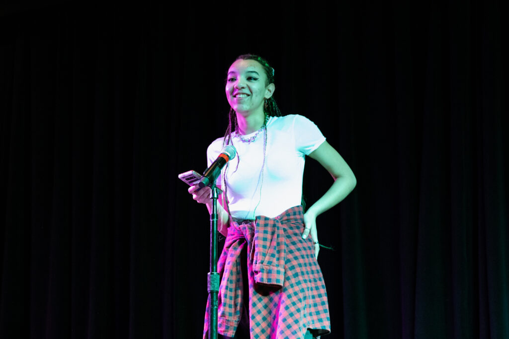 A person smiles while performing poetry 